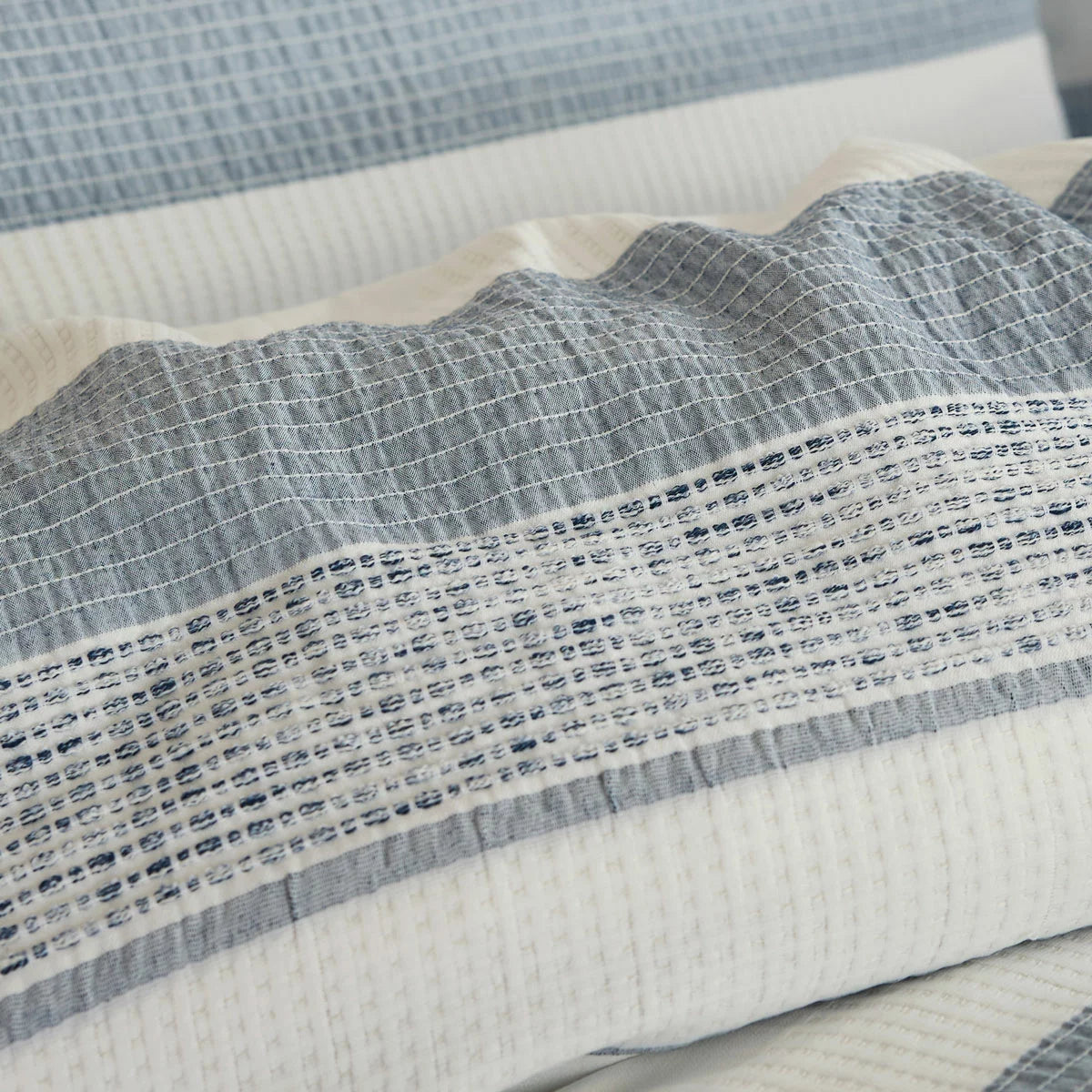 A close-up view of the Belledorm Rahil blue duvet cover set showing the detailed blue and white waffle weave pattern and sturdy button closure.