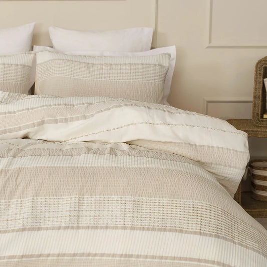 A close-up shot of the Belledorm Rahil natural bedding set showing the contrast between the textured waffle front and the clean stitching lines on a wooden bed frame.