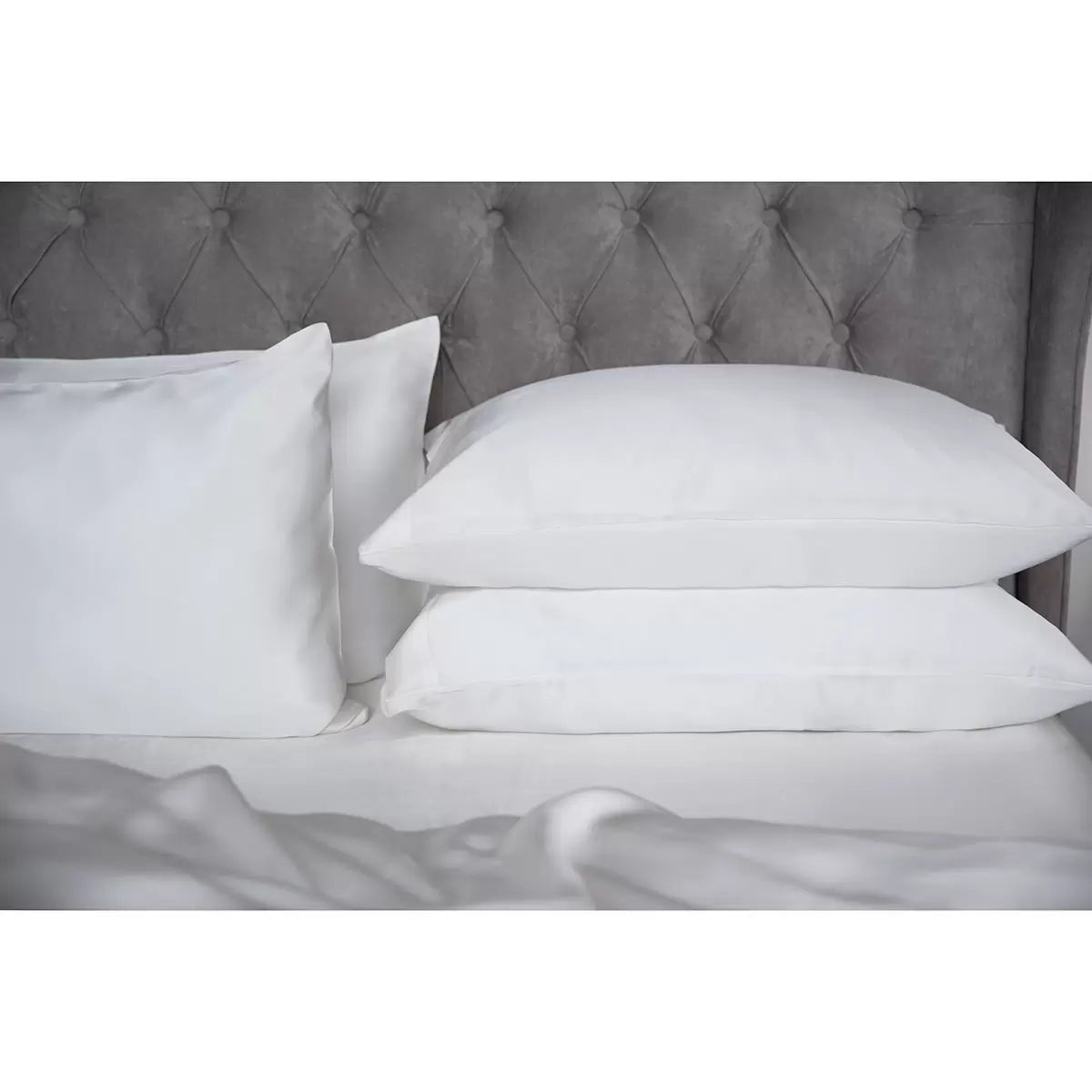 Pair of Belledorm 100% Mulberry silk ivory housewife pillowcases neatly laid out on a plush mattress, highlighting the soft lustrous fabric finish.