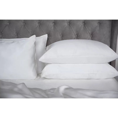 Pair of Belledorm 100% Mulberry silk ivory housewife pillowcases neatly laid out on a plush mattress, highlighting the soft lustrous fabric finish.