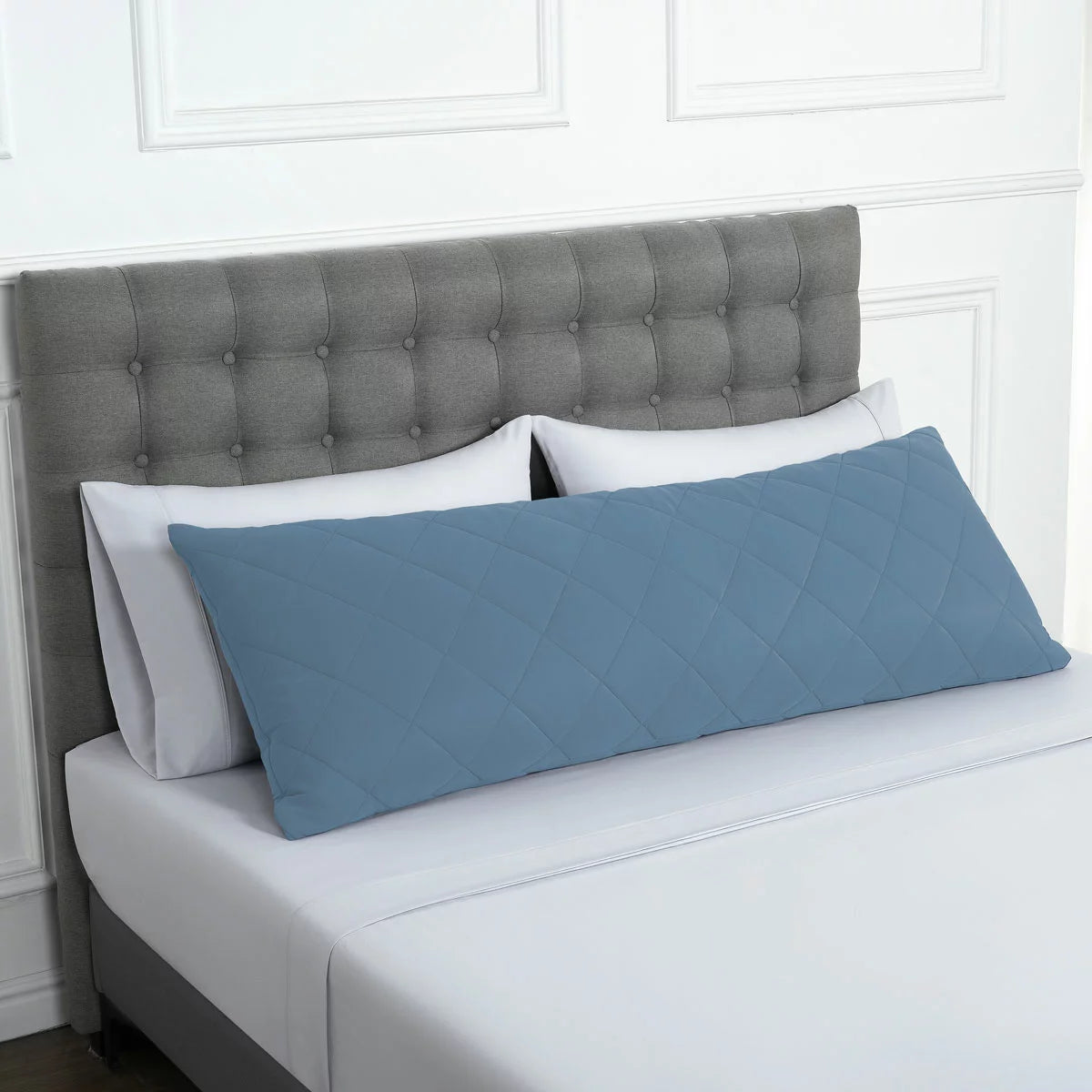 Below Zero cooling body pillow in a soft neutral tone with a textured circular-knit cover resting on a contemporary bed setting.