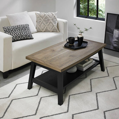 Angle view of the Bentley Designs Camden Coffee Table showing its weathered oak top, brass inlays, and dark peppercorn A-frame legs in a modern living room setting.
