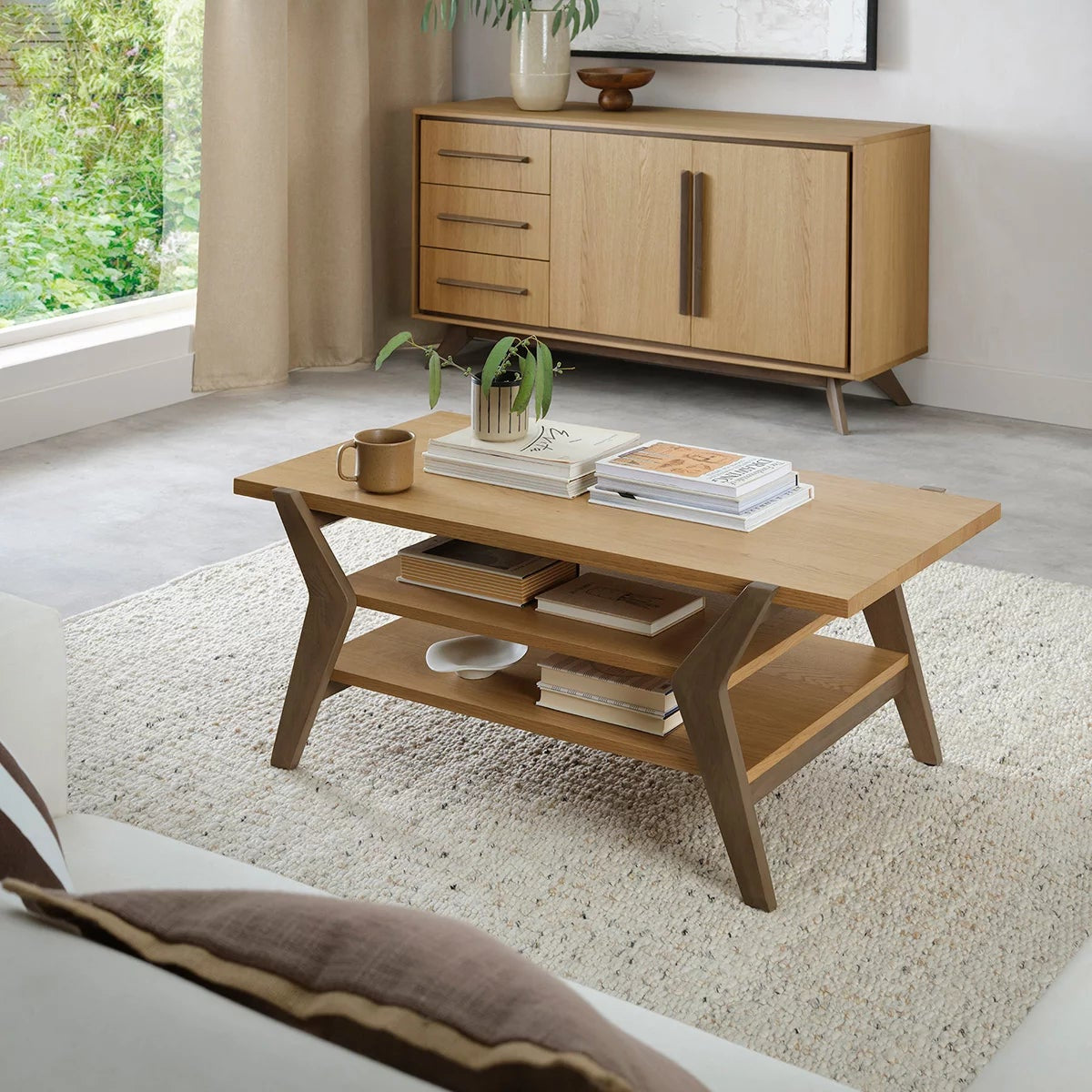 Bentley Designs Kristen light oak oval coffee table featuring a two-tone oak finish, lower open storage shelf, and splayed solid wood legs.