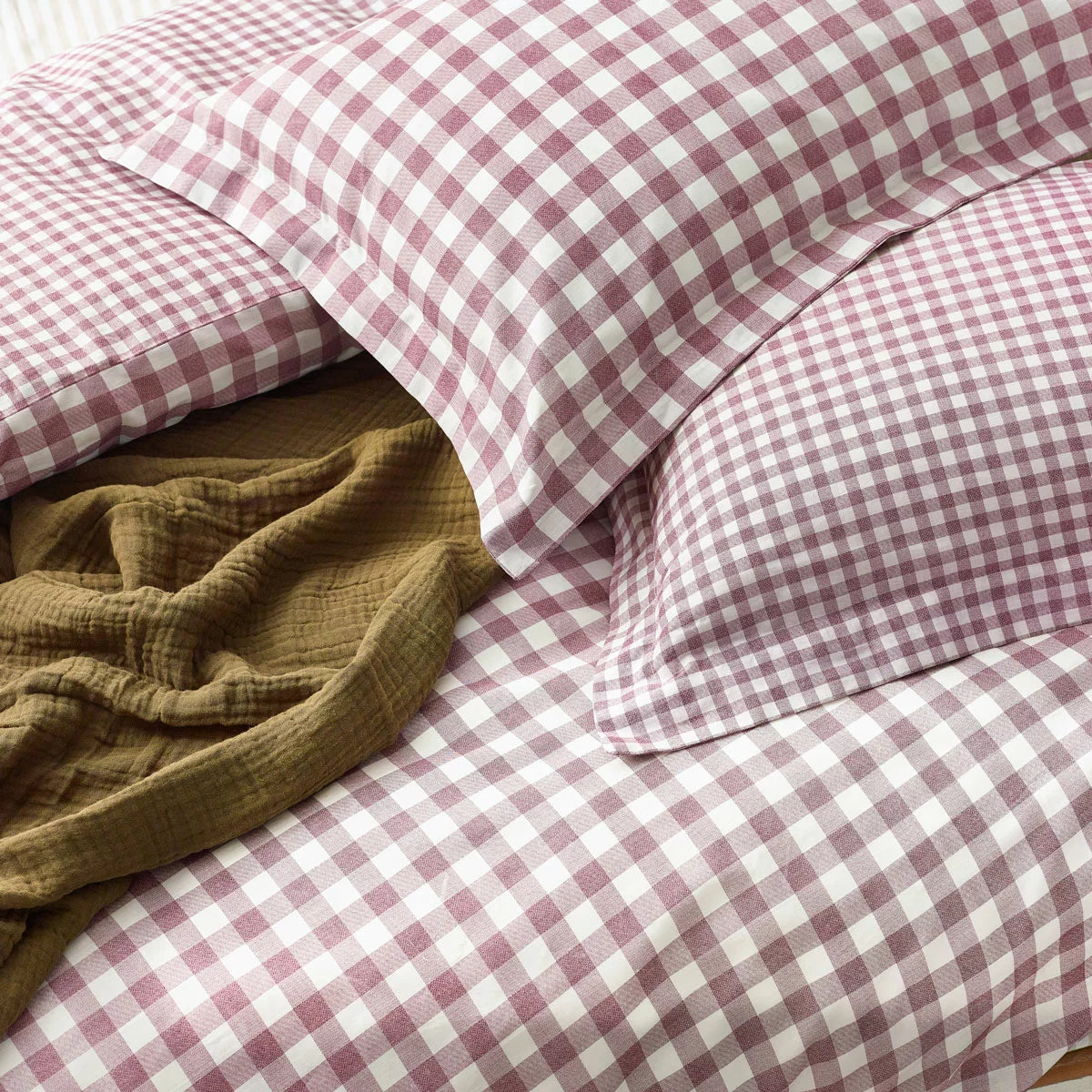 Flat lay of the single Yard Barton 100% cotton duvet cover set in berry gingham on a white wooden bed, showcasing the reversible mélange reverse pattern and neat Oxford border pillowcase.