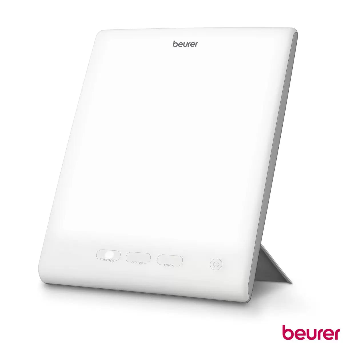 Beurer TL45 white daylight therapy lamp standing on a wooden office desk next to a laptop computer, illuminating the workspace with its bright 10,000 lux LED panel.