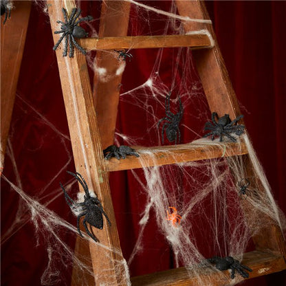 Dense white 240g stretch spider web material stretched intricately across a dark wooden porch for Halloween decorating.