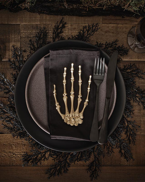 Flat lay view of four rectangular black foliage pattern placemats arranged neatly on a light oak wooden dining table.