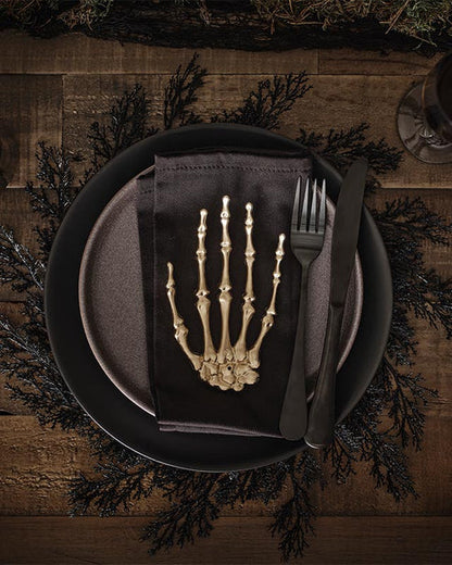Flat lay view of four rectangular black foliage pattern placemats arranged neatly on a light oak wooden dining table.