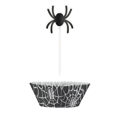 Black spider web cupcake cases with decorative web picks arranged on a wooden serving board alongside Halloween party treats.