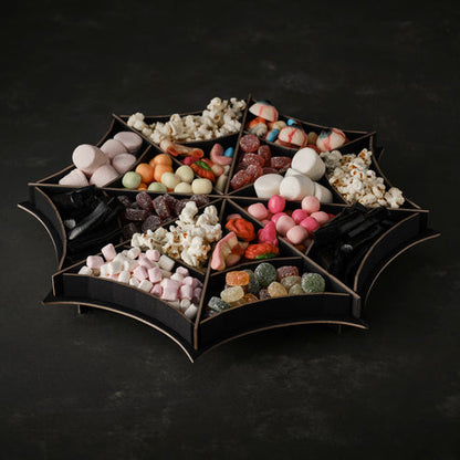 Matte black spider web tiered treat stand holding Halloween cupcakes on a dark party display table.