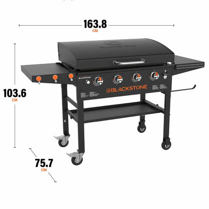 Angle view of the large black 4 burner Blackstone 36 inch gas griddle with hood raised, showing the massive steel cooktop, folded side shelves, and caster wheels on a patio.