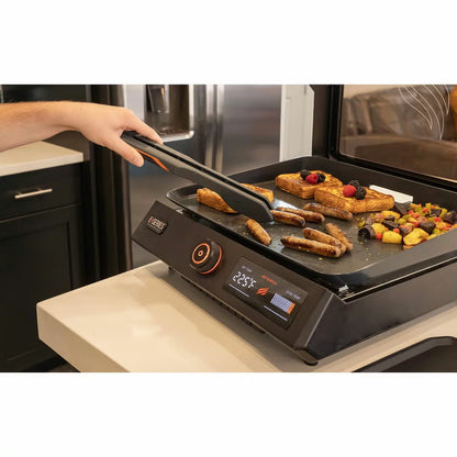 Front view of the black Blackstone E-Series 17 inch electric griddle on a kitchen counter showing the digital LCD screen, glass hood window, and smooth ceramic plate.