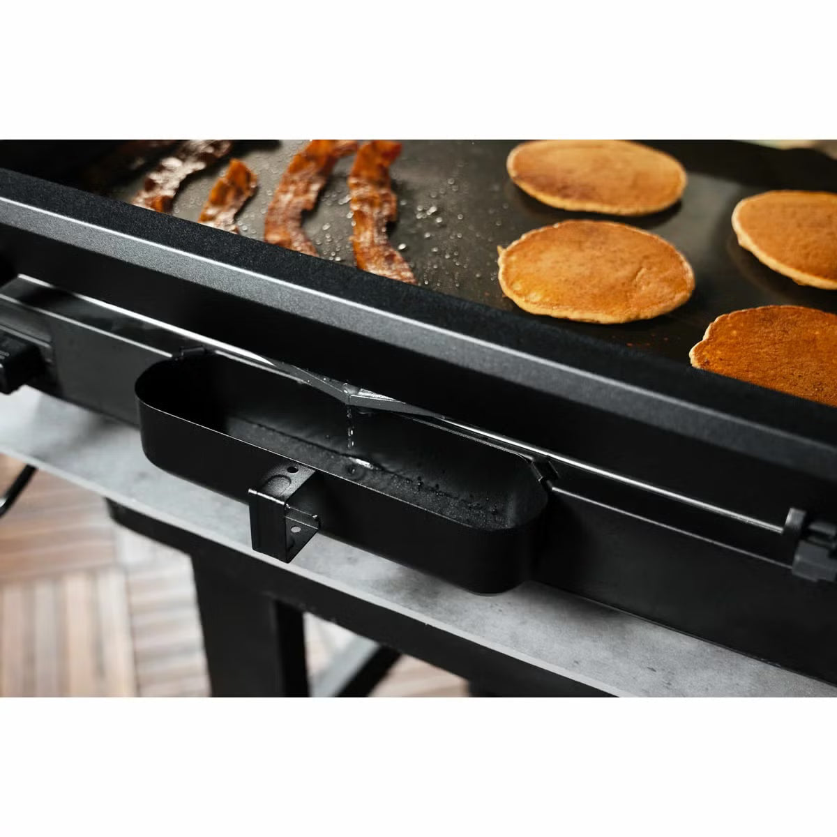 Front view of the black Blackstone E-Series 17 inch electric griddle on a kitchen counter showing the digital LCD screen, glass hood window, and smooth ceramic plate.