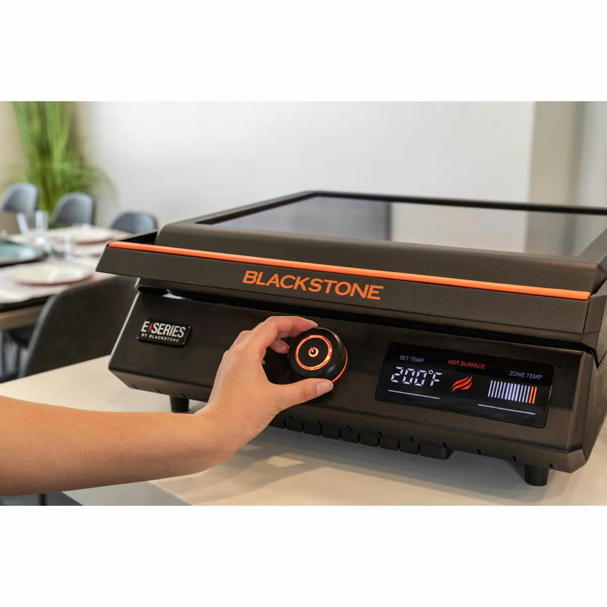 Front view of the black Blackstone E-Series 17 inch electric griddle on a kitchen counter showing the digital LCD screen, glass hood window, and smooth ceramic plate.