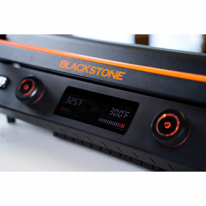 The Blackstone E-Series 22" Electric Griddle with its sleek glass hood and digital control panel, set up on a modern kitchen counter with cooked food ready to serve.