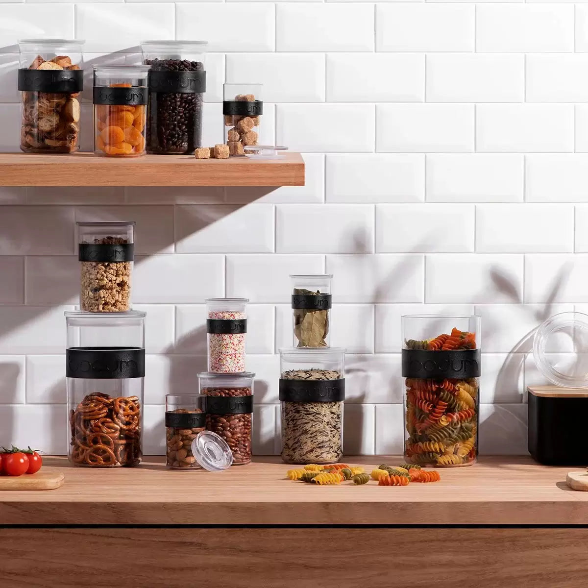 Full set of 12 Bodum PRESSO storage jars displayed on a modern kitchen shelf showing various sizes.