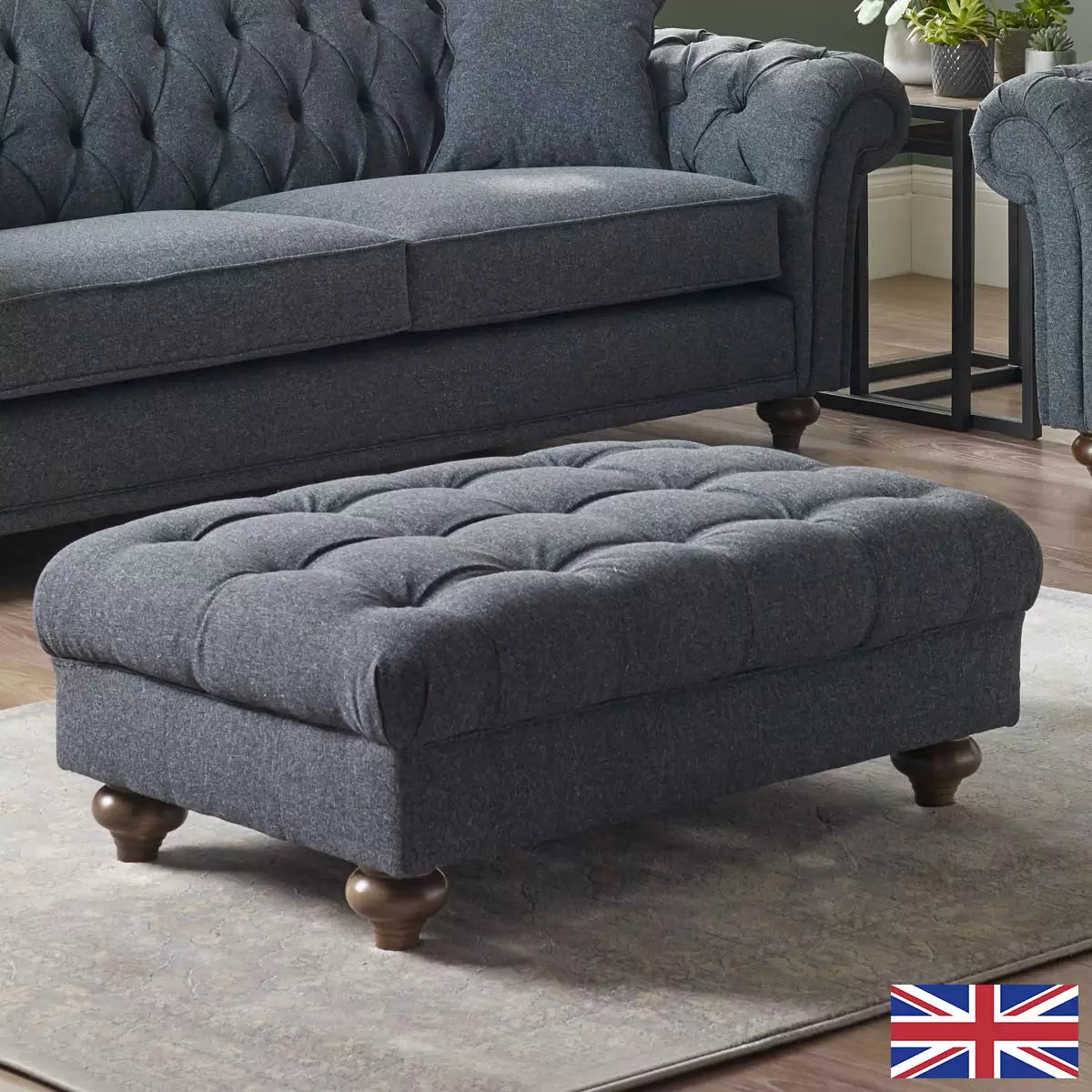 Angled shot of the Bordeaux buttoned fabric footstool in deep blue, showcasing its hand-tied tufting, textured linen-style fabric, and dark stained solid wood legs on a neutral rug.
