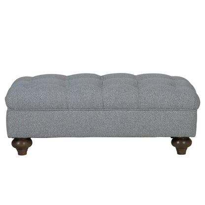 Close-up angle of the grey Bordeaux fabric footstool showing hand-tied button detailing, linen texture, and dark stained wooden legs in a living room setting.