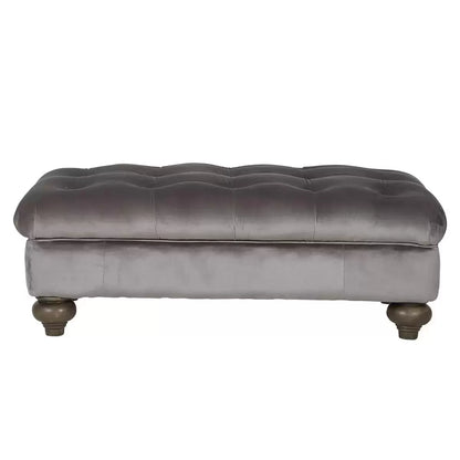 Front angle view of the Bordeaux Grey Velvet Footstool featuring deep hand-tied tufting and dark stained solid wood legs in a modern living room setting.