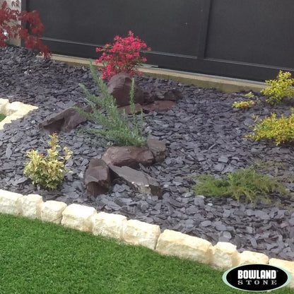 Bowland Stone 20mm Plum Slate displayed in a garden border, showcasing its natural texture and depth of colour.
