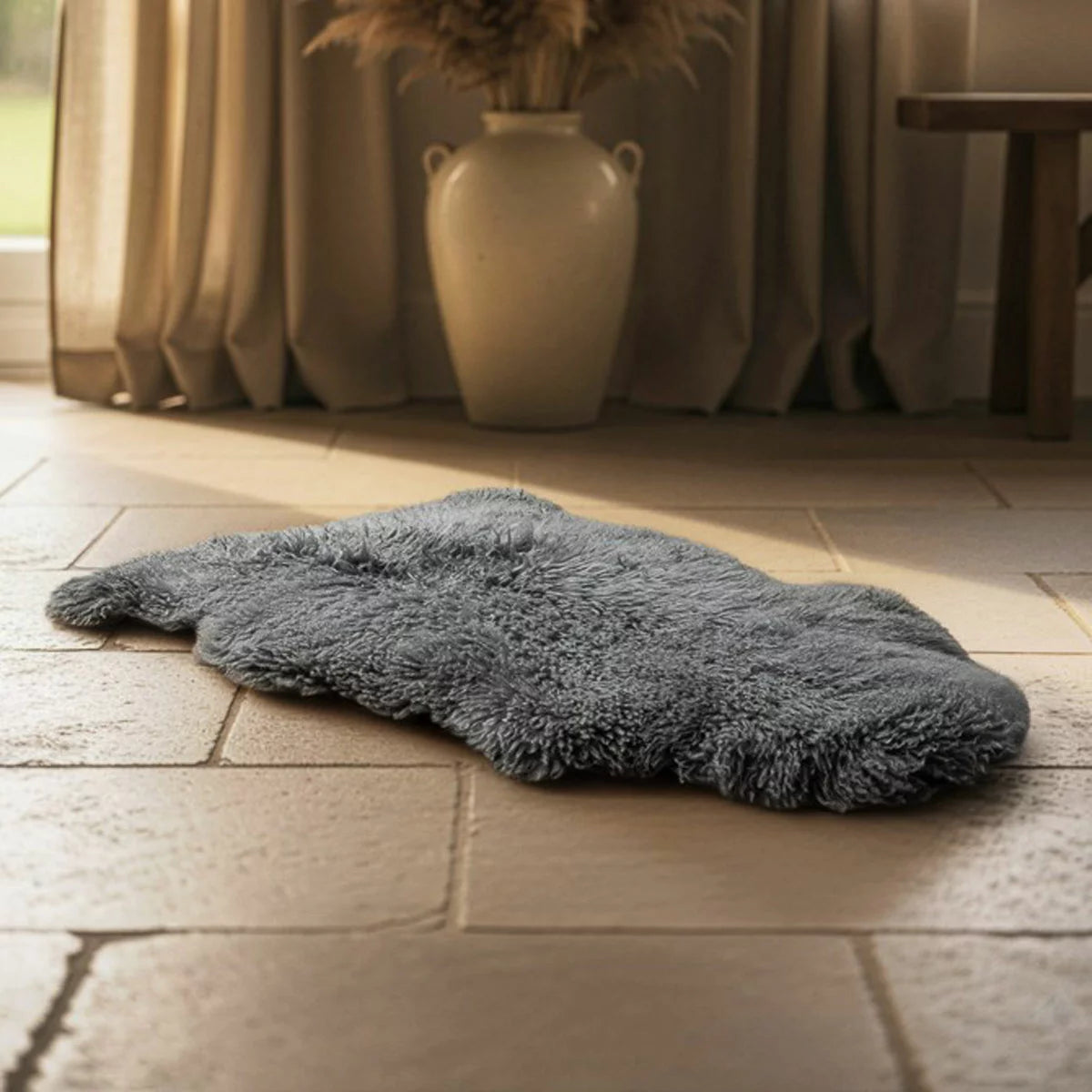 Natural beige Bowron Back Country sheepskin rug with plush curly wool texture draped neatly over a cozy wooden armchair.