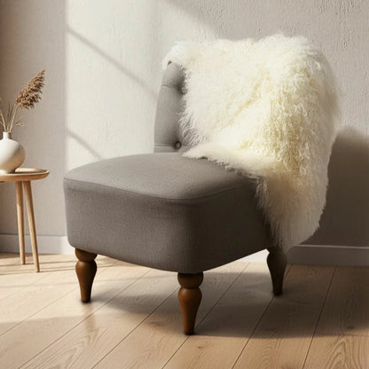 Overhead shot of a soft white Bowron Tibetan Sheepskin Rug draped across a Scandinavian wooden armchair showing long, silky wool curls.