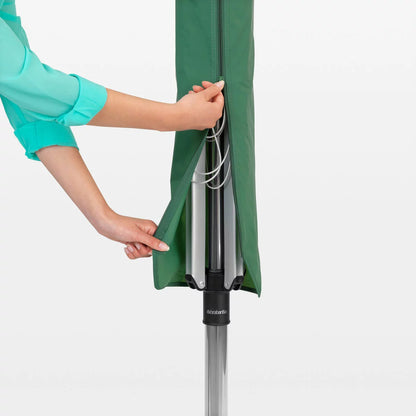 A Brabantia Lift-O-Matic 50m rotary airer standing in a well-maintained garden, featuring taut lines and a protective cover nearby on a clear, sunny day.