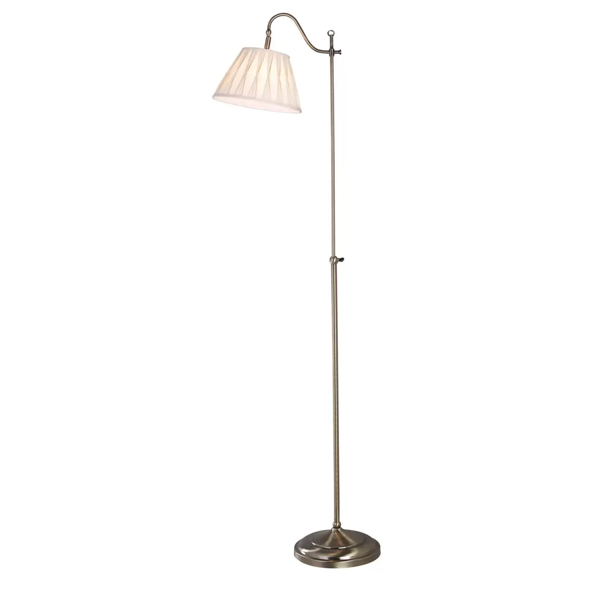 Side view of the Suffolk Rise and Fall Floor Lamp in antique brass, showcasing its adjustable height mechanism and cream pleated faux silk shade next to a classic armchair.