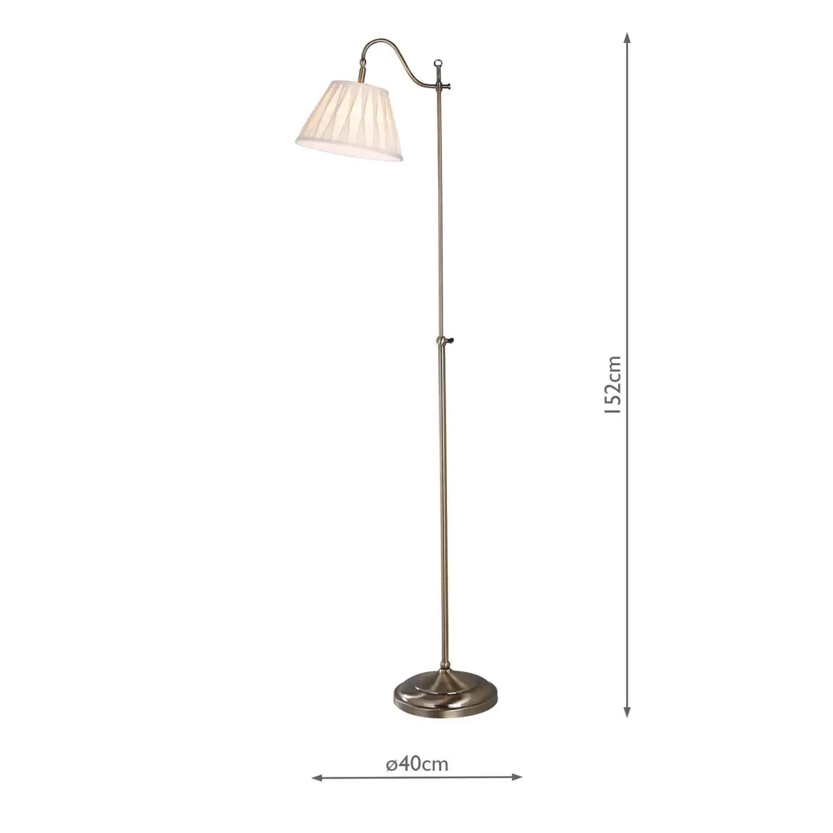 Side view of the Suffolk Rise and Fall Floor Lamp in antique brass, showcasing its adjustable height mechanism and cream pleated faux silk shade next to a classic armchair.