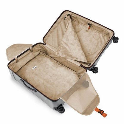 Textured dark metallic Briggs & Riley Torq 78cm Large Spinner Suitcase with molded handles and four dual ball-bearing spinner wheels standing upright on an airport terminal floor.