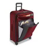 Side angle of black Briggs and Riley ZDX 53cm spinner suitcase showing exterior handle rails and durable corner guards in an airport lounge setting.
