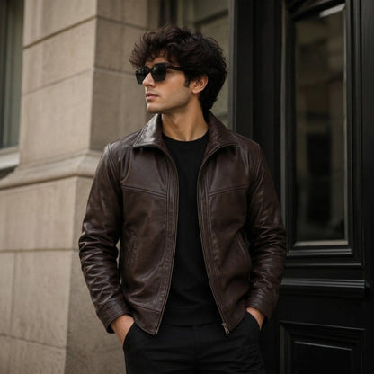 Brown leather jacket for men in a classic cut, photographed from the front on a neutral studio background to show the warm brown tone and smooth leather texture.