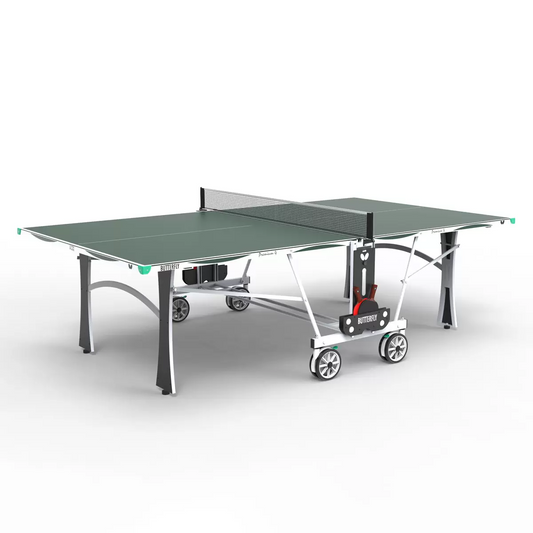Full side view of the blue Butterfly Premium 4 Outdoor Table Tennis Table fully assembled on a backyard stone patio, showing its silver legs and matching green corner bumpers.