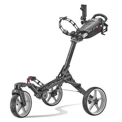 Side view of the grey Caddytek CaddyLite Auto+360 aluminium golf trolley parked on a lush green fairway, showcasing its wide-profile wheels and folded umbrella accessory in the holder.
