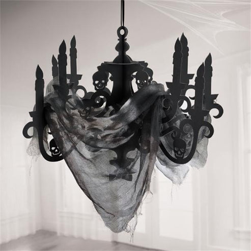 Black cardboard candelabra decoration with draped black gauze fabric hanging against a dark Halloween party background.
