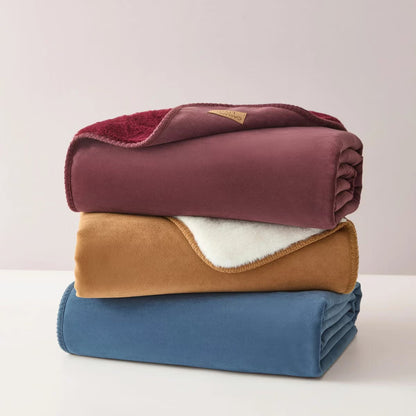 Soft Casual Living Luxe throw blanket folded on a modern sofa showing the velvety faux suede side, plush faux fur reverse, and whipstitched border detail.