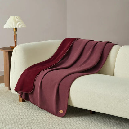 Soft Casual Living Luxe throw blanket folded on a modern sofa showing the velvety faux suede side, plush faux fur reverse, and whipstitched border detail.