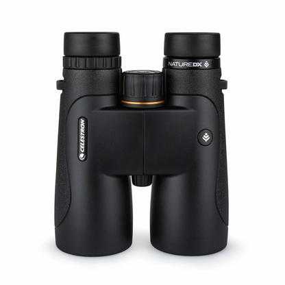 Front angle view of the dark green Celestron Nature DX 10x50mm binocular showing the massive multi-coated objective lenses resting on a mossy rock.