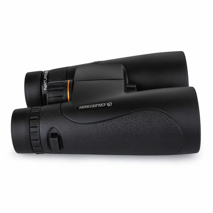 Front angle view of the dark green Celestron Nature DX 10x50mm binocular showing the massive multi-coated objective lenses resting on a mossy rock.