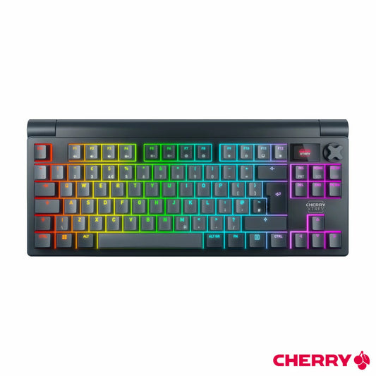 Top-down angled view of the black Cherry XTRFY MX 8.3 TKL wireless mechanical keyboard on a dark desk mat, highlighting the vibrant RGB illumination, crisp PBT keycaps, and active glowing LCD display screen.