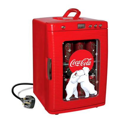 Vibrant red Coca-Cola 25L mini fridge with polar bear graphics and chrome handles, glowing with LED interior light through its tempered glass door on a sleek desk.