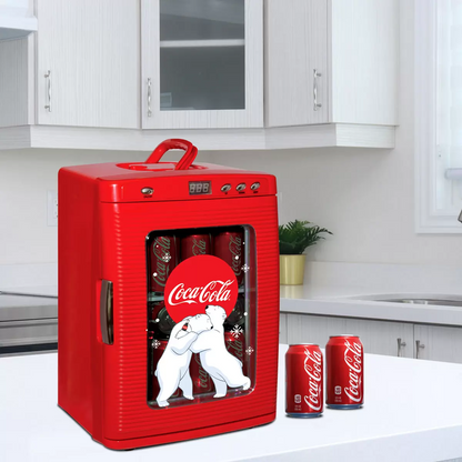 Vibrant red Coca-Cola 25L mini fridge with polar bear graphics and chrome handles, glowing with LED interior light through its tempered glass door on a sleek desk.