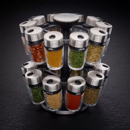 Stainless steel Cole & Mason 20 jar spice carousel filled with colorful herbs and spices sitting on a clean granite kitchen countertop.