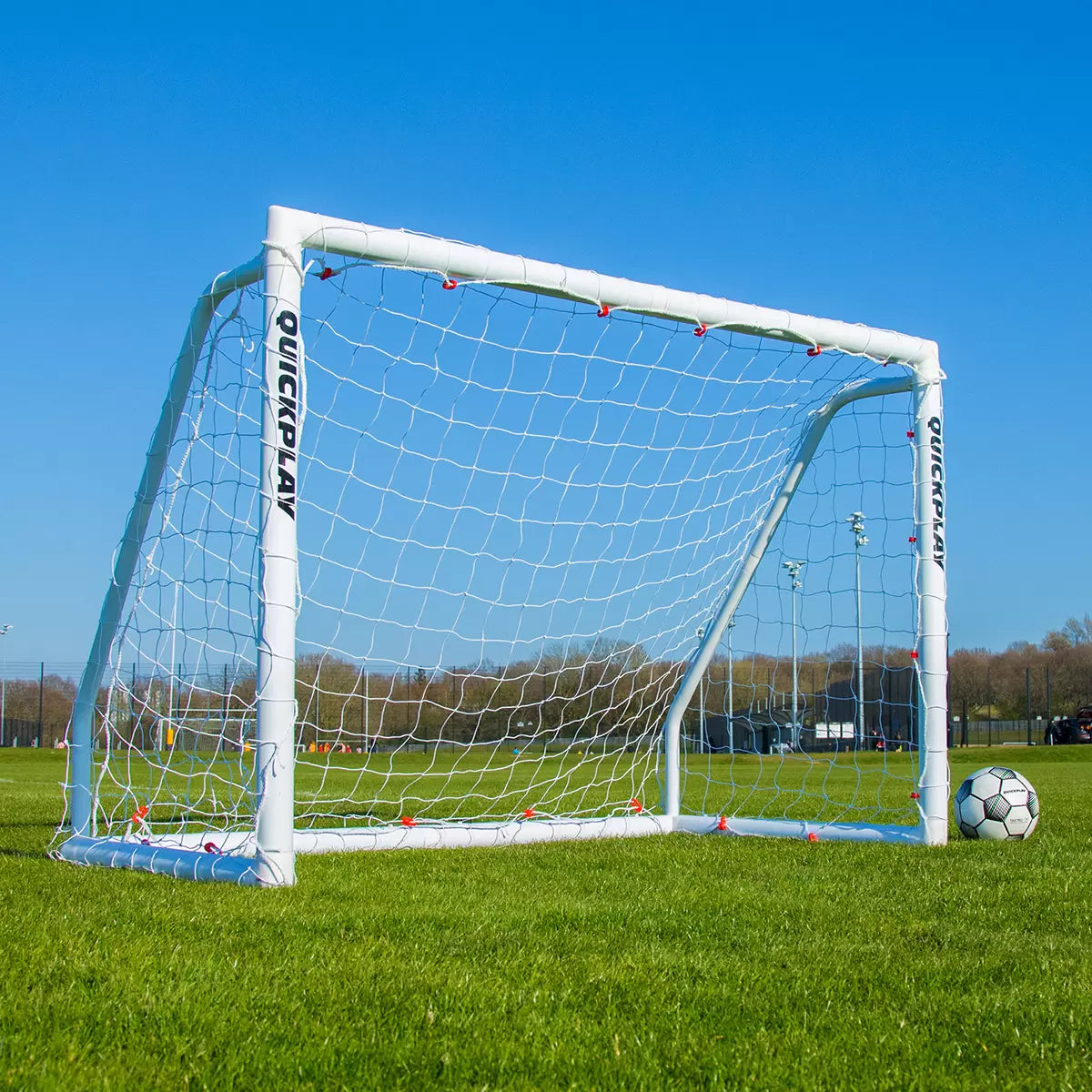 Front angle view of the white Quickplay Q-Fold 6x4 football goal standing secure on a green turf field with its net fully tensioned.
