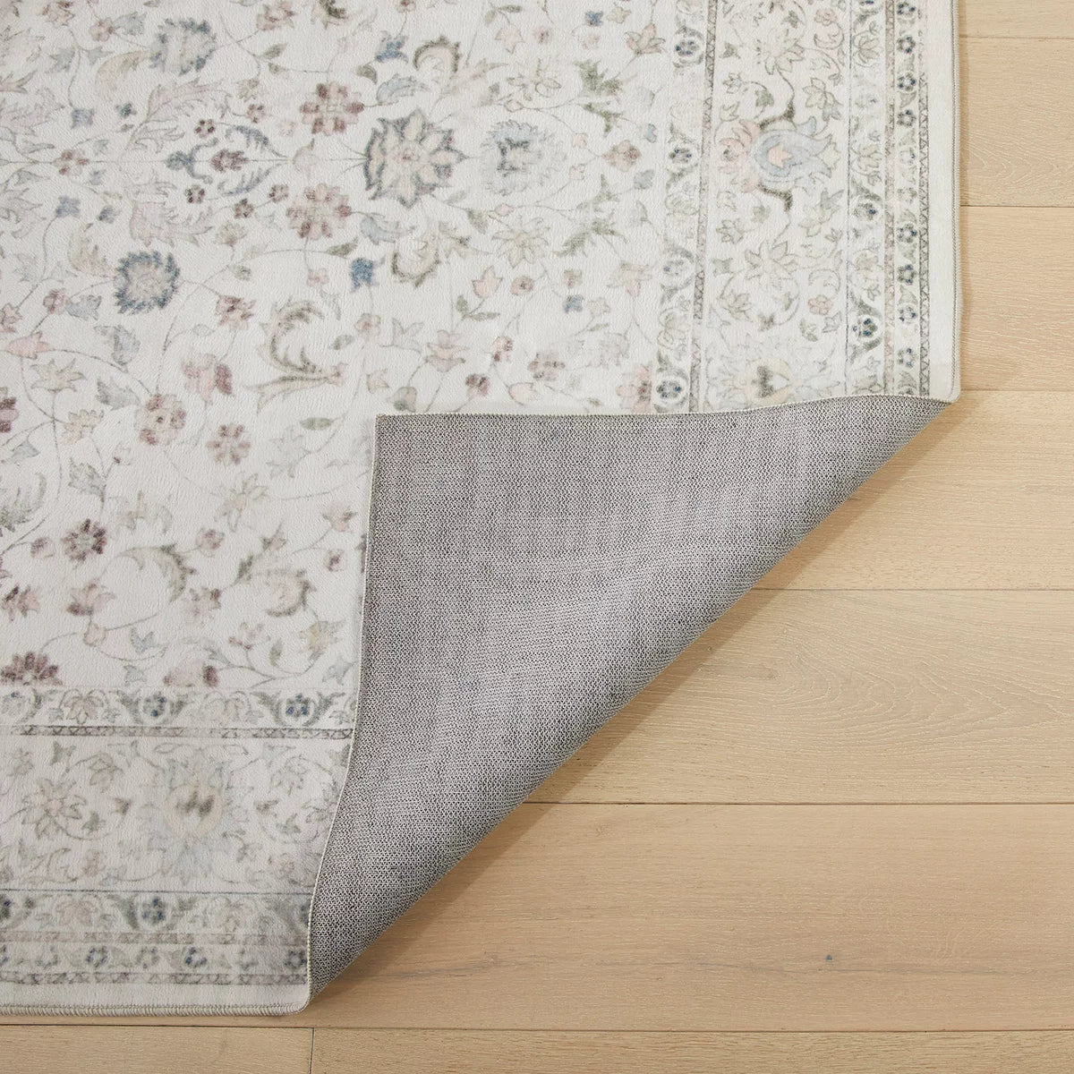 Flat-lay angle of the cream Concept Looms Liberty Washable Rug resting on a dark wood floor showing its soft 4mm velvet surface and finished edges.