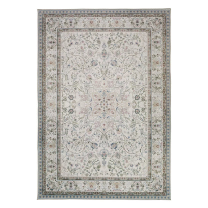 Top-down view of the soft pastel pink and grey Concept Looms Liberty Washable Rug resting smoothly on a light hardwood floor next to a modern sofa.
