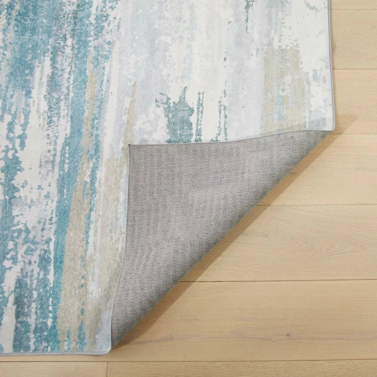 Concept Looms Liberty Sky Washable Rug 120x180cm featuring a smooth sky-blue velvet surface and non-slip backing laid on light wood flooring.