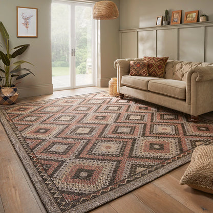 Concept Looms Sumac flatweave rug featuring warm brown and rust geometric patterns displayed on a outdoor wooden deck.