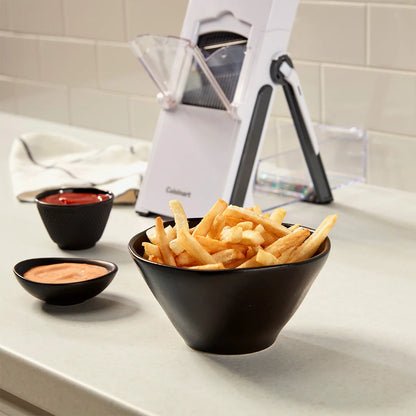 The Cuisinart PrecisionSlice Upright Mandoline standing on a counter, showcasing its extra-wide feed tube, control knob, and attached clear collection container.