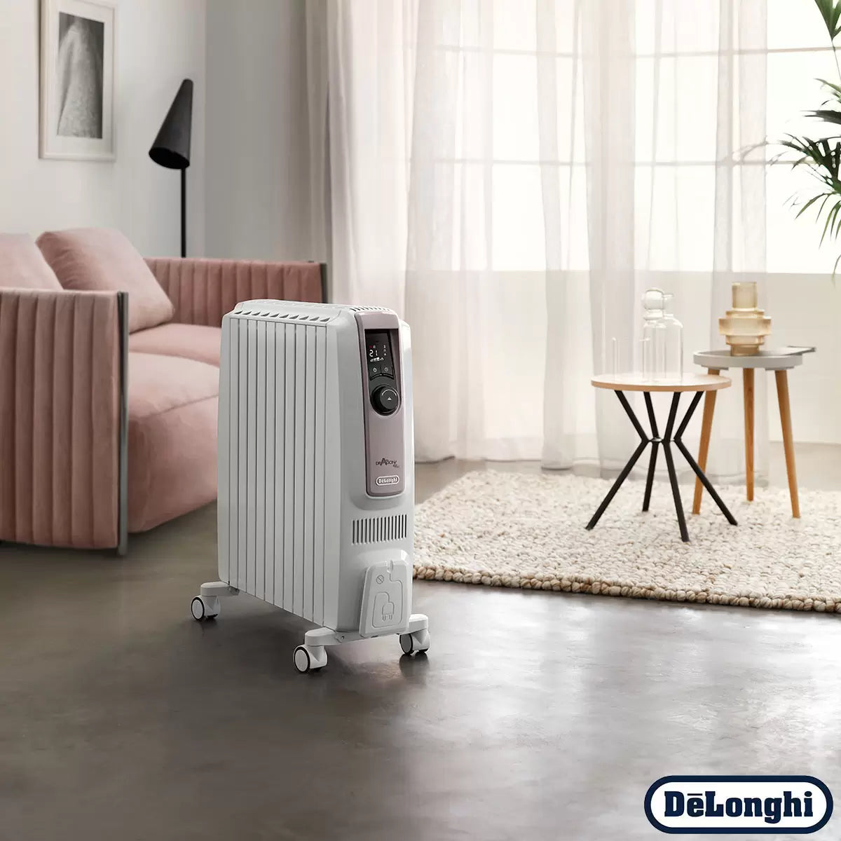 Front three-quarter view of the white De'Longhi Dragon 4 oil-filled radiator standing on a wooden floor showing the digital LED display screen and side chimney fins.